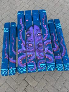 Painted Adirondack picnic table depicting a purple octopus in an ocean