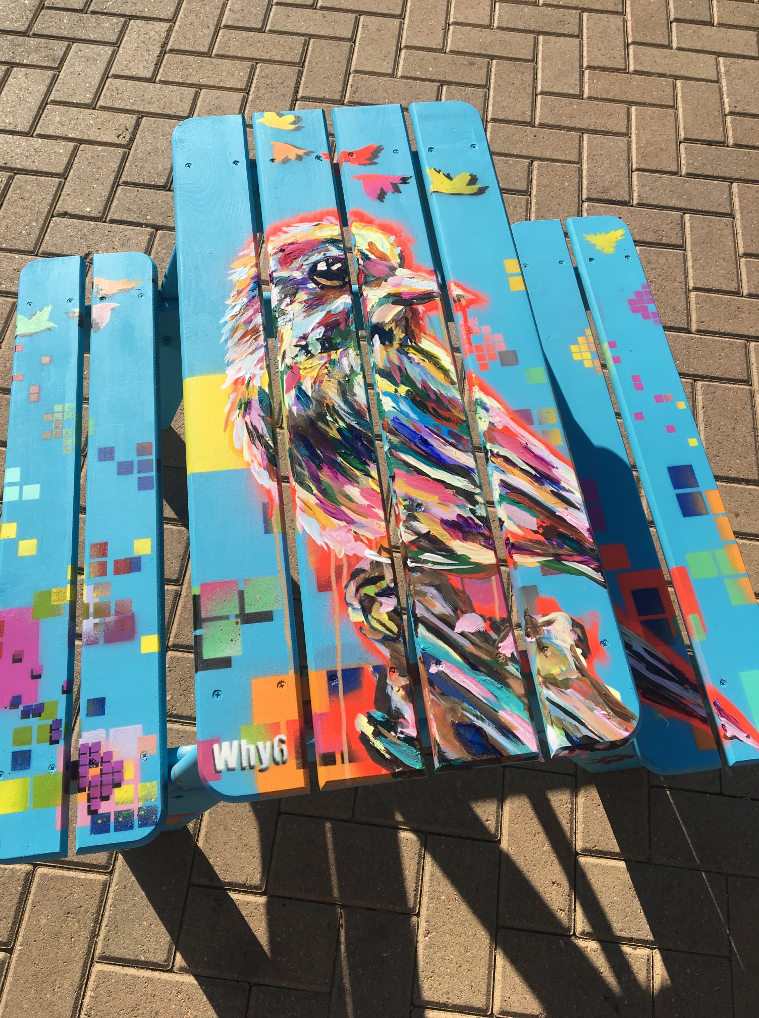 Painted Adirondack picnic table depicting a colorful bird with digital boxes in the background