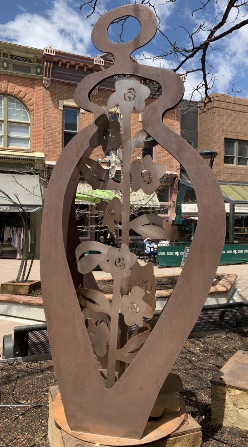 Metal sculpture of an outline of a body with growing flowers inside