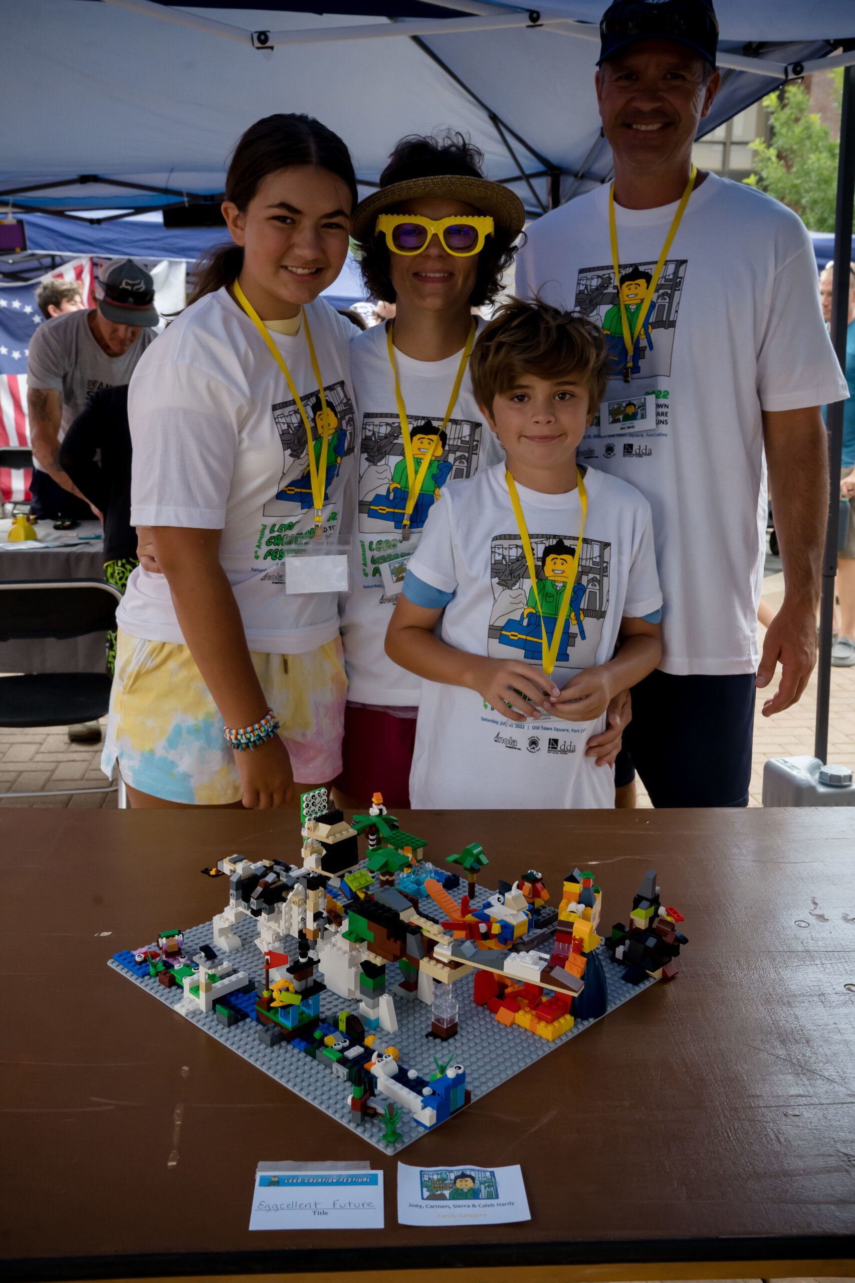 Family posing in front of their colorful LEGO® Creation