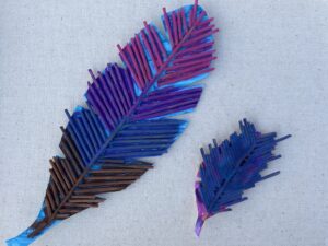 Crafting project of spaghetti noodles glued together to look like a feather with multiple colors