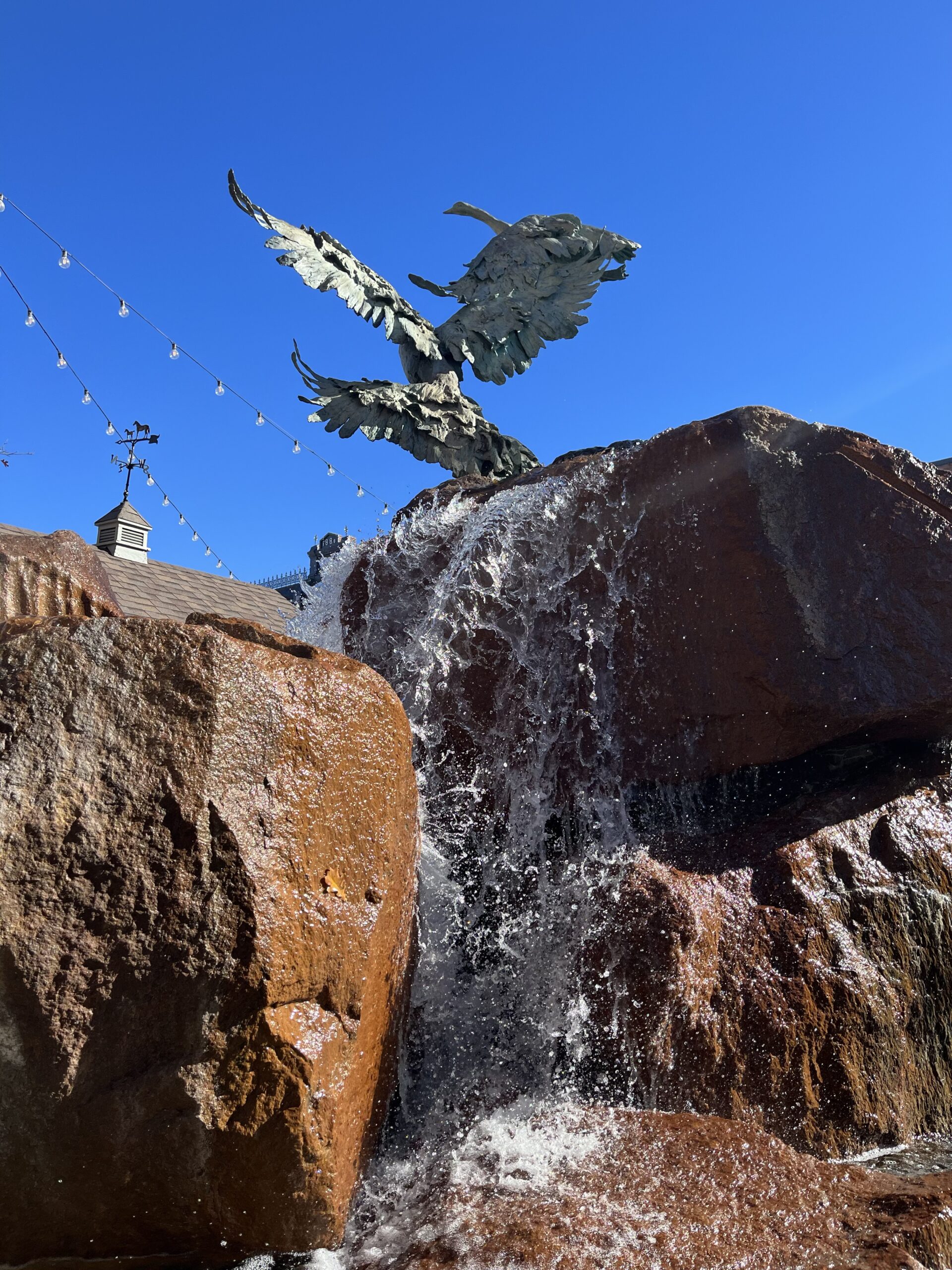 A picture of the grease statue above a water feature in downtown Fort Collins