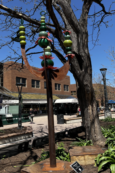 A sculpture with four prints of bright green balls of various sizes on galvanized steel.