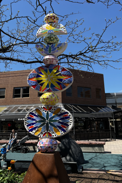 A totem sculpture with colored-looking disco balls and between bright circular star-like images on concrete discs.
